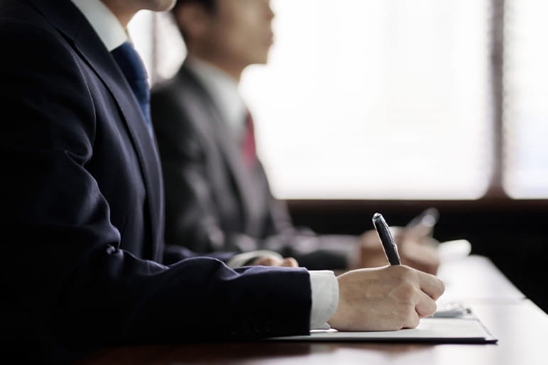 スーツ姿でメモを取る新入社員の写真