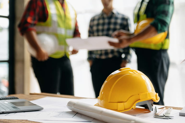 ヘルメットと図面が置かれた会議の様子