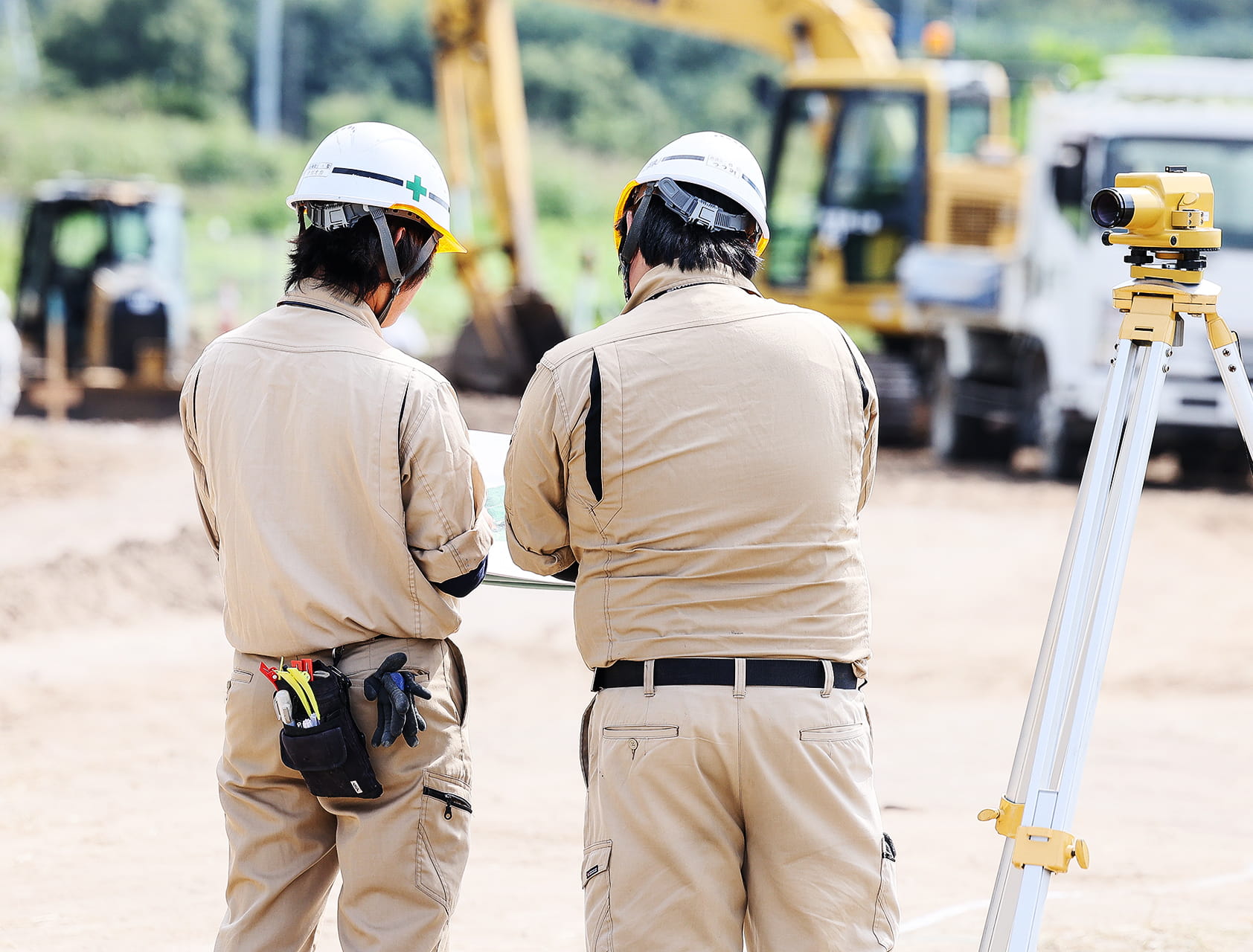 建設現場で図面を確認する作業員の写真