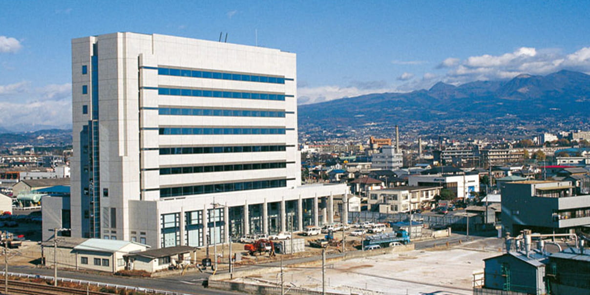 都市に建つ白い大型オフィスビルの全景