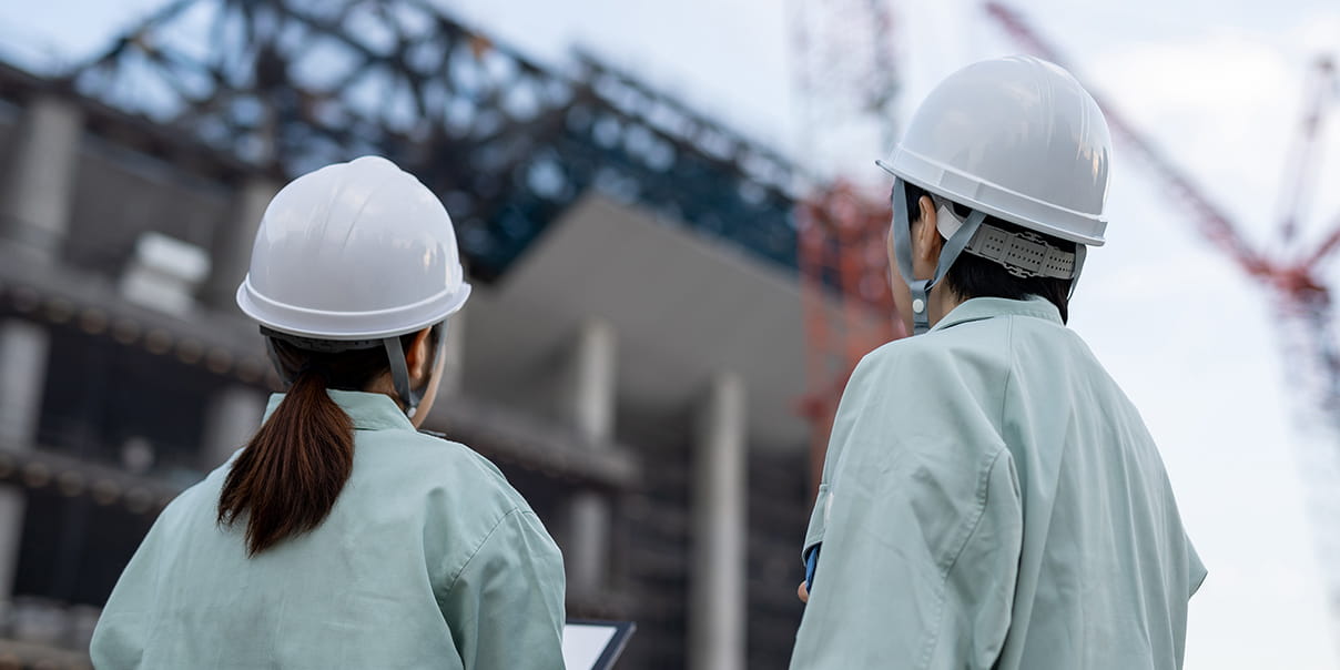 ヘルメットを着用した2人が建設現場を見ている様子