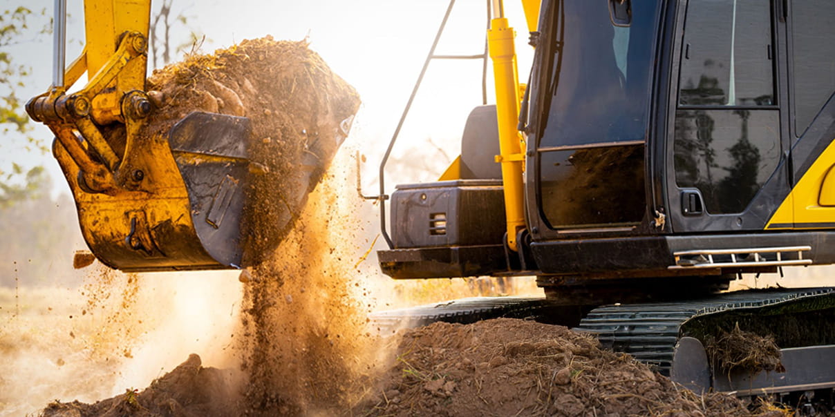 黄色のショベルカーのバケット部分から土がこぼれ落ちている様子