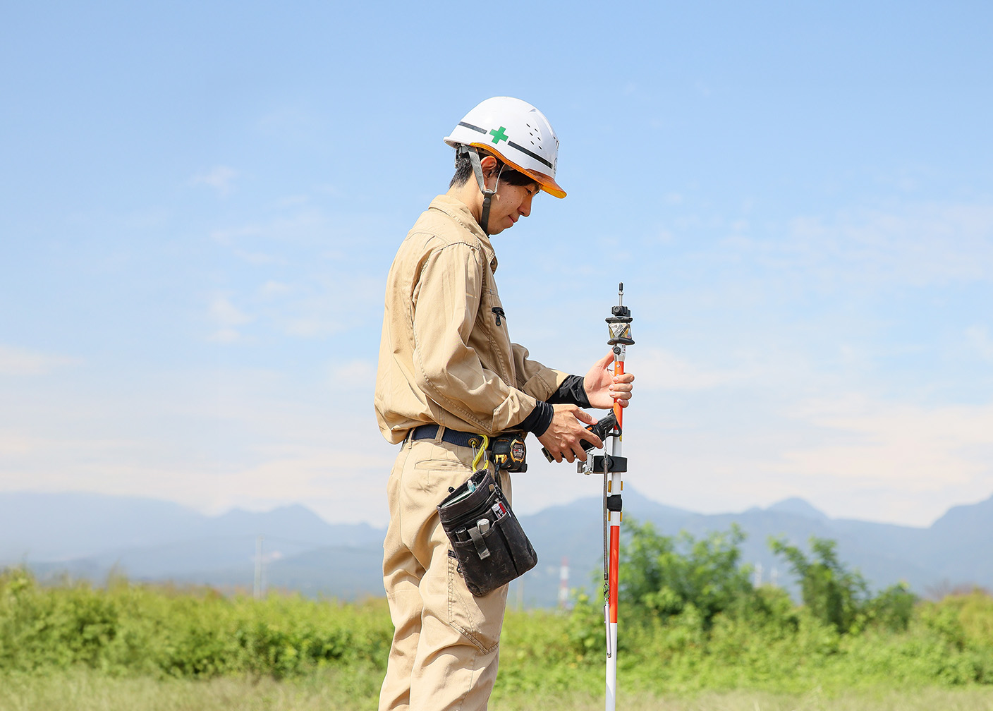 作業員が測量機器を手に持ち、屋外で作業している姿