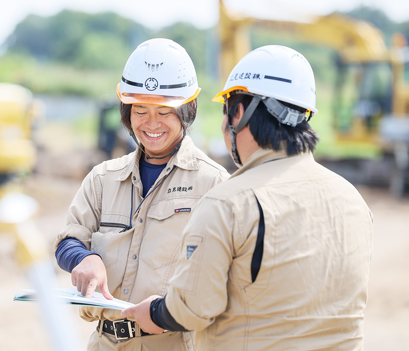 作業員が建設現場で図面を見ながら打ち合わせをしている姿