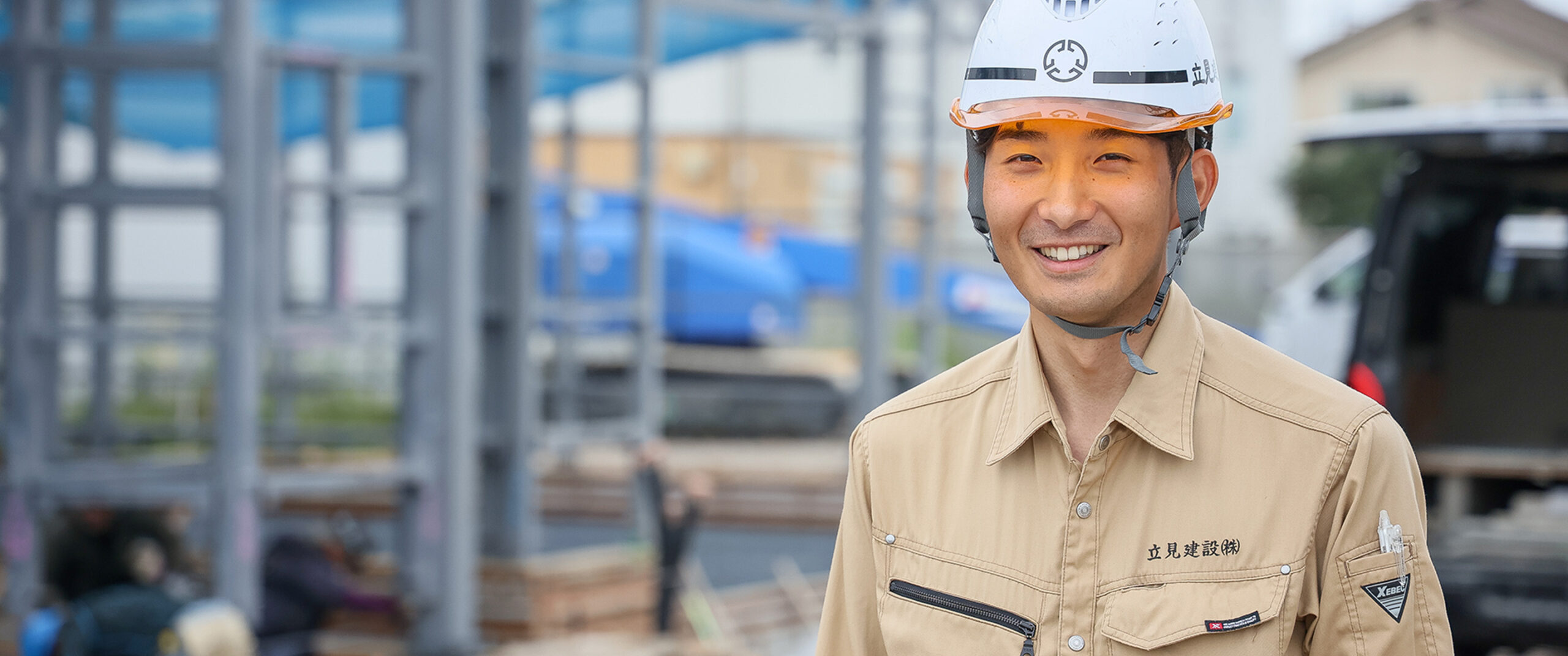 ヘルメットを被った作業員が笑顔を見せている姿