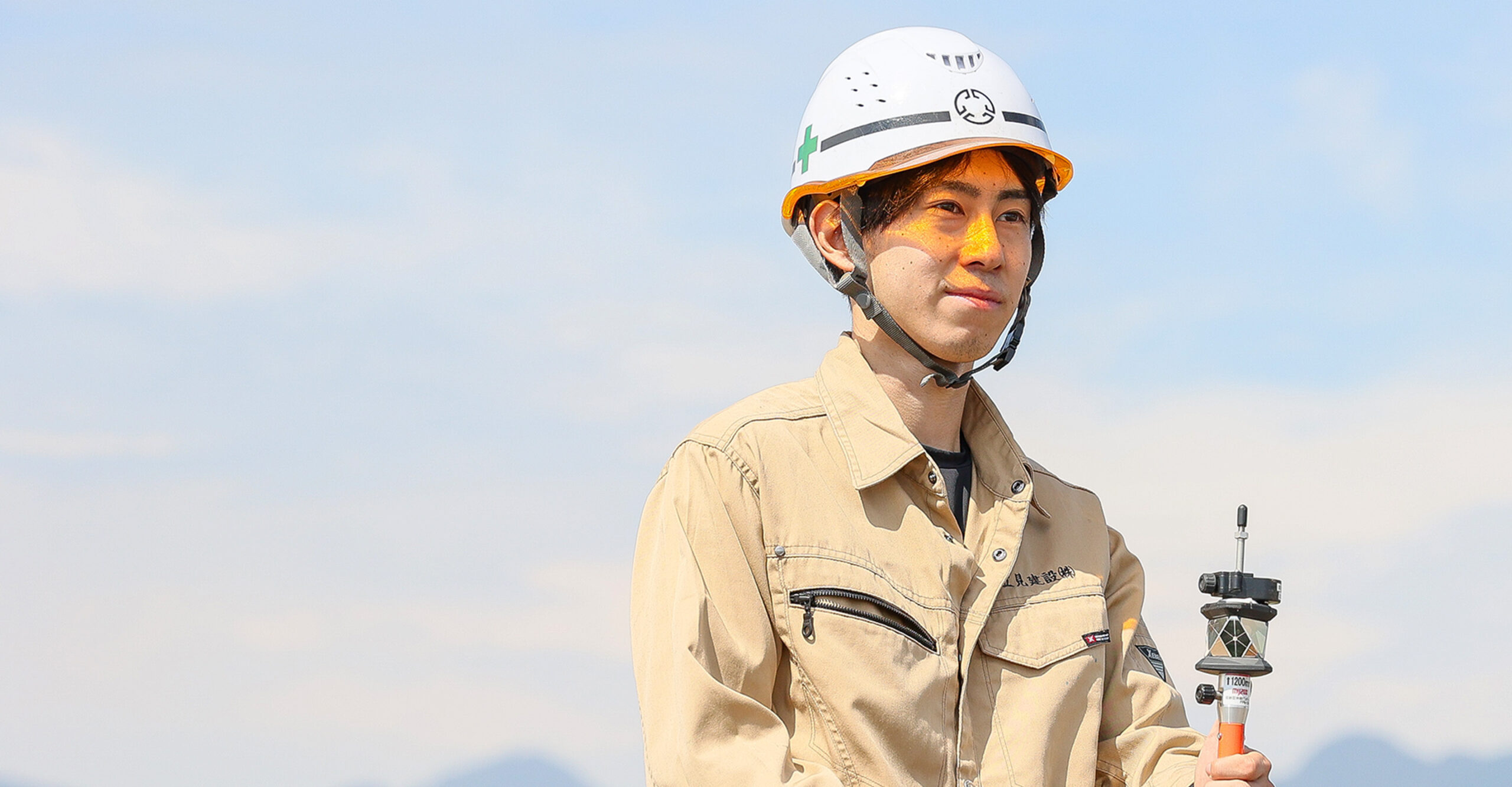 作業員が測量機器を手に持ち、屋外で作業している姿